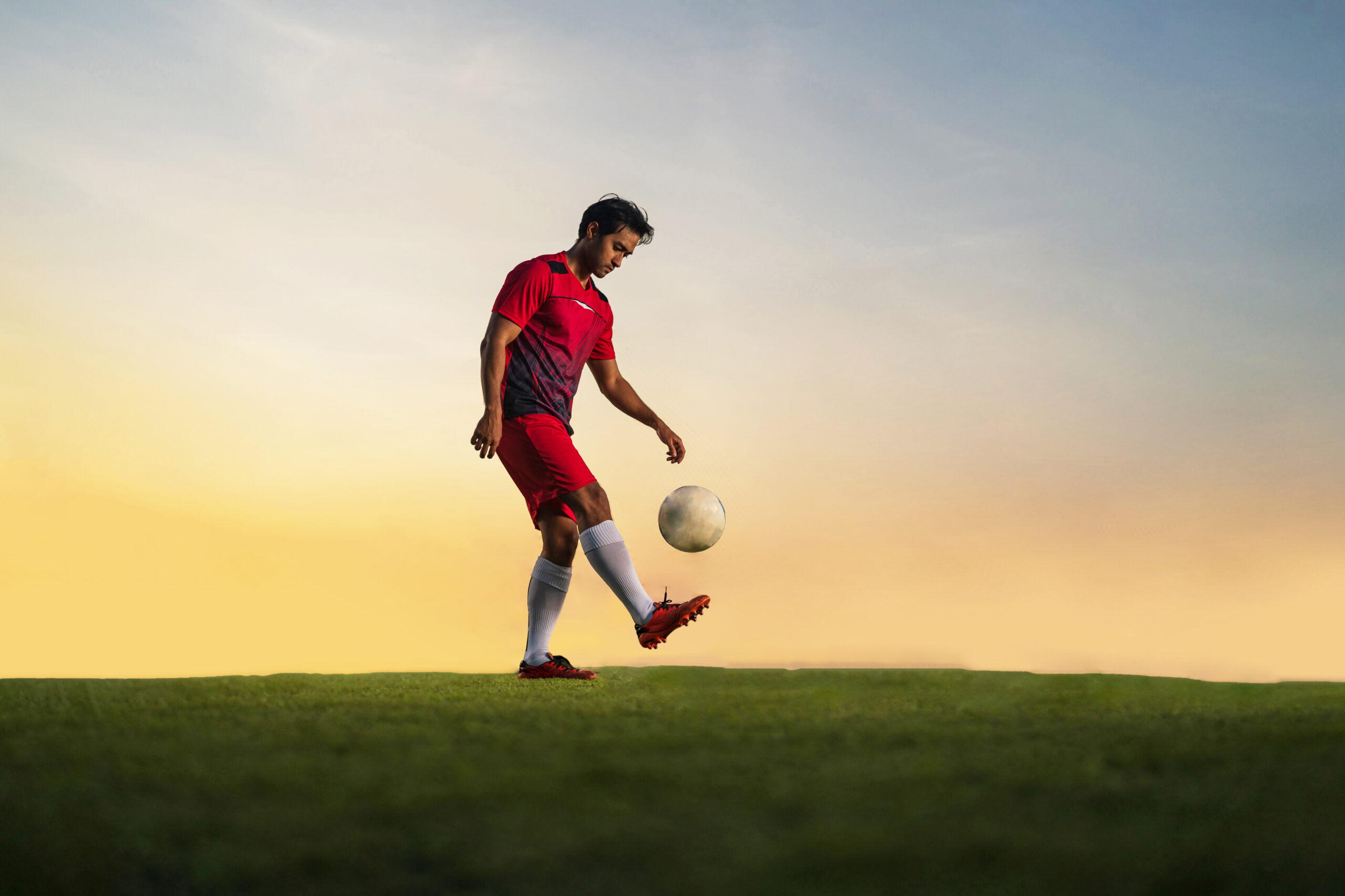 Football player playing ball in the outdoor stadium at sunset.